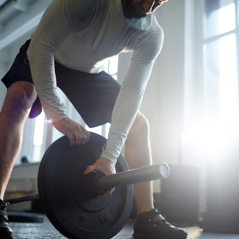 Человек поднимает штангу